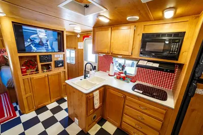 a small kitchen with a sink and a tv at Darling Daisy Retro RV Adventure in El Cajon