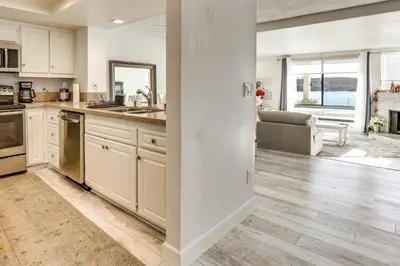 a kitchen with white cabinets and a living room at Waterfront Condo with Dock Access in Carlsbad! in Carlsbad
