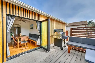 a deck with a couch and a table and a grill at House Kitsune - Steps to Beach in Oceanside