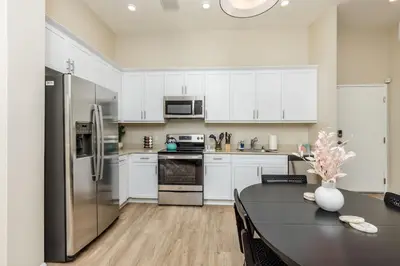 a kitchen with white cabinets and a black table and a refrigerator at Eclectic Fast Wi-Fi Parking Pets Bohemian in San Diego