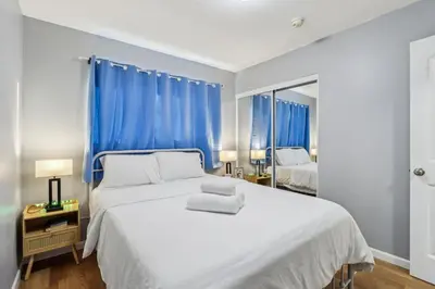 a bedroom with a large white bed with blue curtains at Entire Private Home with 3 Bedrooms, Gated Yard, Parking, King Bed, Available Now in Spring Valley