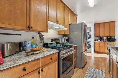 a kitchen with wooden cabinets and a stainless steel refrigerator at Entire Private Home with 3 Bedrooms, Gated Yard, Parking, King Bed, Available Now in Spring Valley