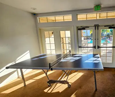 a ping pong table in a room with windows at Ocean View, Sand, Waves & Wonder in Dana Point