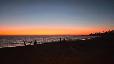 a group of people standing on the beach at sunset at Ocean View, Sand, Waves & Wonder in Dana Point