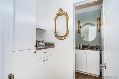 a bathroom with white cabinets and a mirror at Top Floor Oceanfront Condo in San Diego