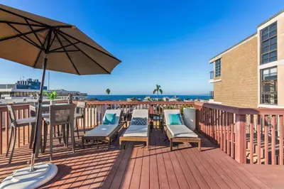 a deck with chairs and an umbrella and the ocean at Grand Retreat Rooftop Bliss and Ocean Views in San Diego