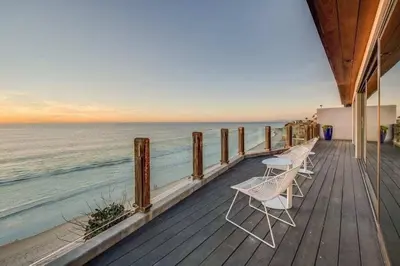 a wooden deck with two chairs and the ocean at Hi-Tech Hideaway - Modern & Ocean Front! in Solana Beach