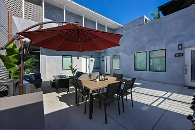 a patio with a wooden table and a red umbrella at Harborside Suite 12 with Hot Tub and King Beds in San Diego
