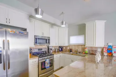 a kitchen with white cabinets and a stainless steel refrigerator at Coastal Haven in San Diego