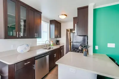 a kitchen with brown cabinets and a green wall at Manhattan Shores 1B in San Diego