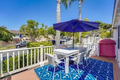 a table and chairs with an umbrella on a balcony at Coral Cottage in San Diego