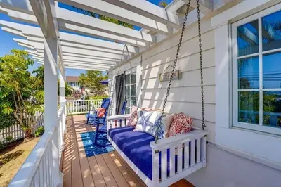 a porch swing on a white house at Coral Cottage in San Diego