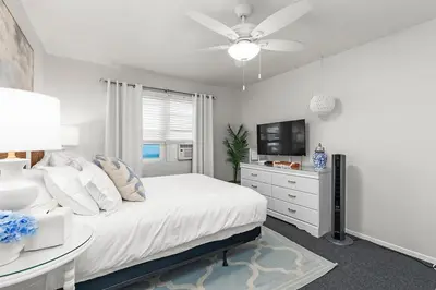 a white bedroom with a bed and a tv at Bayfront 1-BR with Stunning View Steps to the Sand in San Diego