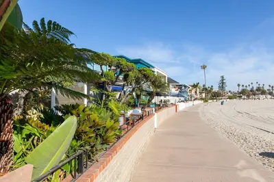 a sidewalk next to a beach with palm trees and houses at Bayfront 1-BR with Stunning View Steps to the Sand in San Diego