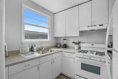 a white kitchen with white cabinets and a window at 500 ft to Ocean Relaxing stay Parking WiFi 838 in San Diego