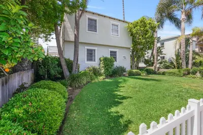 a white fence in front of a house with a yard at 500 ft to Ocean Relaxing stay Parking WiFi 836 in San Diego