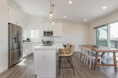 a white kitchen with a wooden table and a dining room at Outsite San Diego - Encinitas Avocado in Encinitas