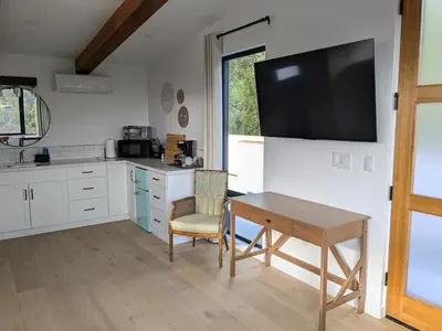 a kitchen with a table and a television on the wall at Newly Built, secluded, and tranquil Nest in Olivenhain in Encinitas