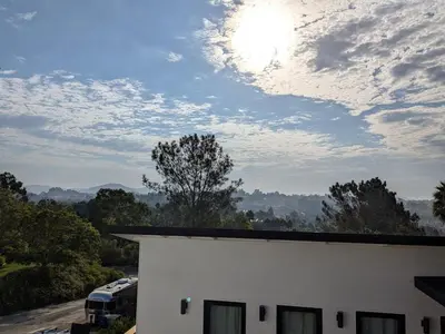 a cloudy sky above a white building with cars parked at Newly Built, secluded, and tranquil Nest in Olivenhain in Encinitas
