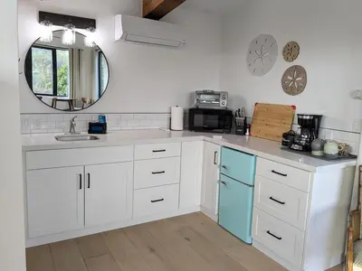 a kitchen with white cabinets and a sink and a mirror at Newly Built, secluded, and tranquil Nest in Olivenhain in Encinitas