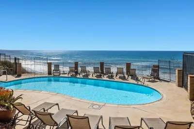 a swimming pool with chairs and the ocean in the background at Breathtaking Bungalow - DMST22 in Solana Beach