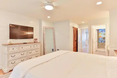 a white bedroom with a large bed and a flat screen tv at Breathtaking Bungalow - DMST22 in Solana Beach