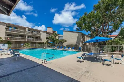 a swimming pool with chairs and a table and an umbrella at Oceanfront Sea'batical - SBTC212 in Solana Beach