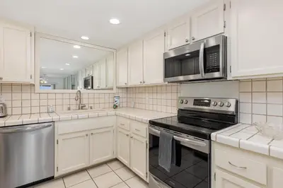 a kitchen with white cabinets and a stove and microwave at Surf, Sun, Sand - SUR106 in Solana Beach
