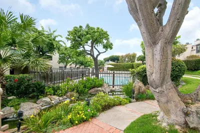a garden with a fence and trees and flowers at Adventure Awaits - SUR15 in Solana Beach