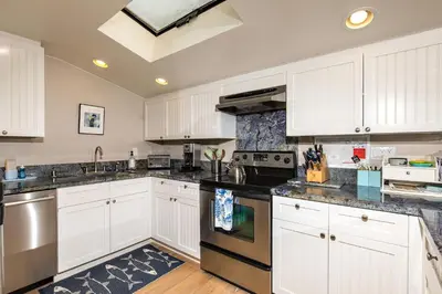 a kitchen with white cabinets and black counter tops at High Tides & Good Vibes SUR169 in Solana Beach