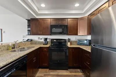 a kitchen with wooden cabinets and a stainless steel refrigerator at Slow M'ocean - DMBC853A in Solana Beach