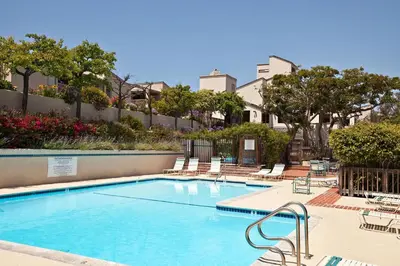 a swimming pool with lounge chairs in a resort at Beach You To It! - SUR61 in Solana Beach