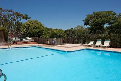 a large swimming pool with chairs and a fence at Beach You To It! - SUR61 in Solana Beach