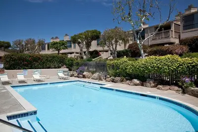 a large swimming pool with chairs and a house at Cast-a-Waves - SUR29 in Solana Beach