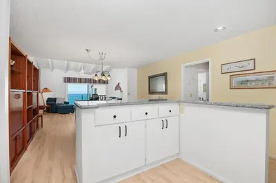a kitchen with white cabinets and a living room at Once Upon A Tide - SBTC312 in Solana Beach