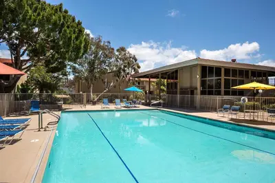 a large swimming pool with chairs and a building at Once Upon A Tide - SBTC312 in Solana Beach