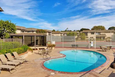 a swimming pool with chairs and a tennis court at Drift Away - DMBC884 in Solana Beach