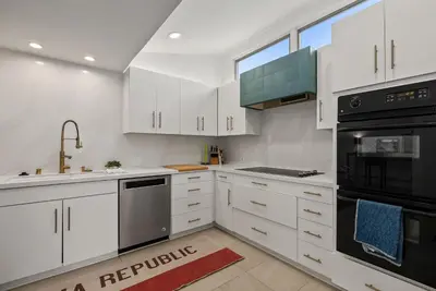 a kitchen with white cabinets and black appliances at Hacienda Palms - SUR168 in Solana Beach