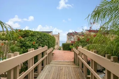 a wooden walkway leading to a house with flowers at Sea For Miles - SUR93S in Solana Beach