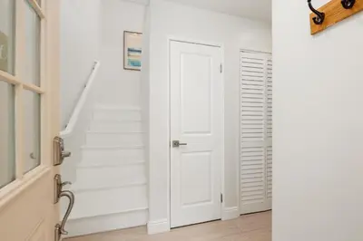 a hallway with a white door and stairs at Solana Escape - SUR44 in Solana Beach