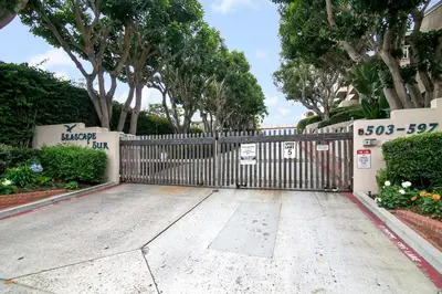 a gate in a driveway with trees and bushes at Salty Shores - SUR108 in Solana Beach