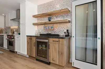 a kitchen with wooden cabinets and a stone wall at Fairway Haven - CB2507 in Carlsbad