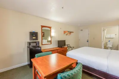 a bedroom with a bed and a desk and a table at Hotel Avenida, San Clemente Beach in San Clemente