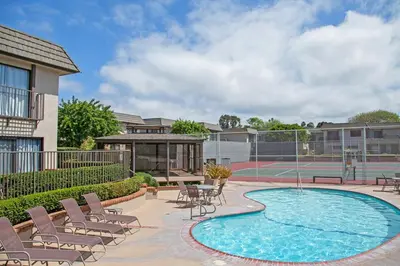 a swimming pool with chairs and a tennis court at Beachy Keen & Cleen - DMBC148S in Solana Beach