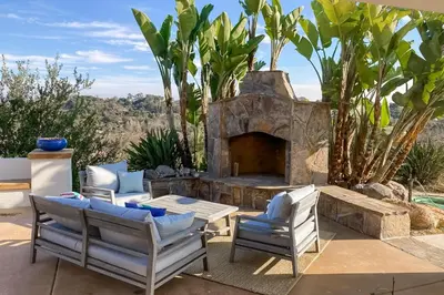 a patio with two chairs and a stone fireplace at Canyon Paradise in Encinitas