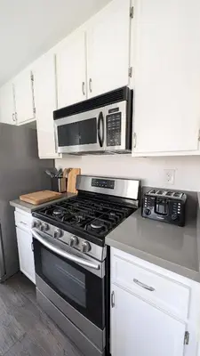 a kitchen with a stove and a microwave at Poolside 2BR Condo with Balcony & Workspace in San Diego