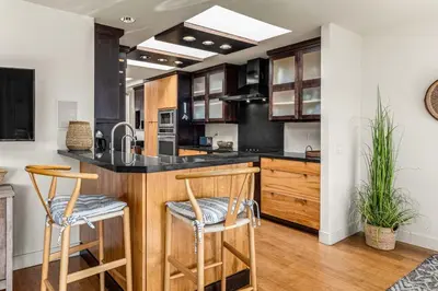 a kitchen with wooden cabinets and a counter with stools at Coastal View at Torrey Pines townhouse in San Diego