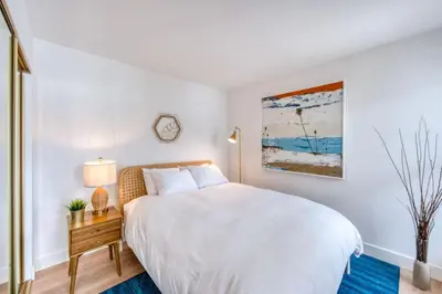 a white bedroom with a large bed and a table at Ocean Harbor View Dana Point in Dana Point