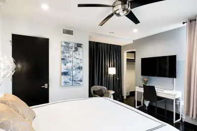 a bedroom with a bed with a ceiling fan and a desk at Hotel-Style Independent Suite in Ocean Beach in San Diego