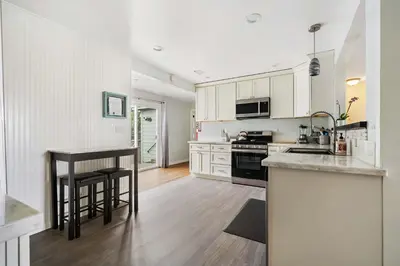 a kitchen with white cabinets and a table and a counter at O-Side Beach Bungalow with Jaccuzi Blocks to beach in Oceanside